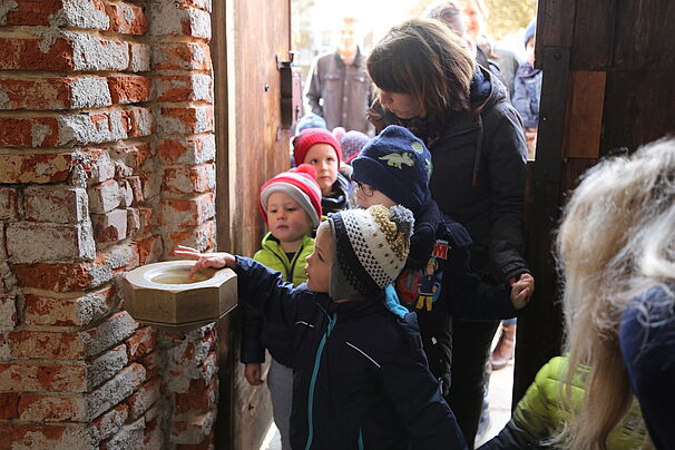 Kinder kommen in die Kirche und tauchen Finger ins Weihwasserbecken 