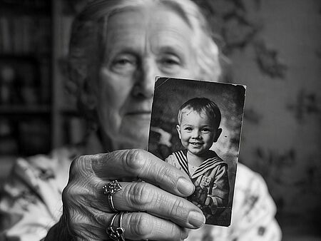 Alte Frau mit Kinderbild in der Hand