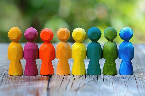 Acht bunte Spielfiguren aus Holz stehen nebeneinander