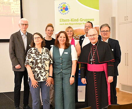 Gruppenfoto von Vertreterinnen und Vertretern der Eltern-Kind-Gruppen gemeinsam mit Bischof Rudolf Voderholzer vor einem Werbebanner
