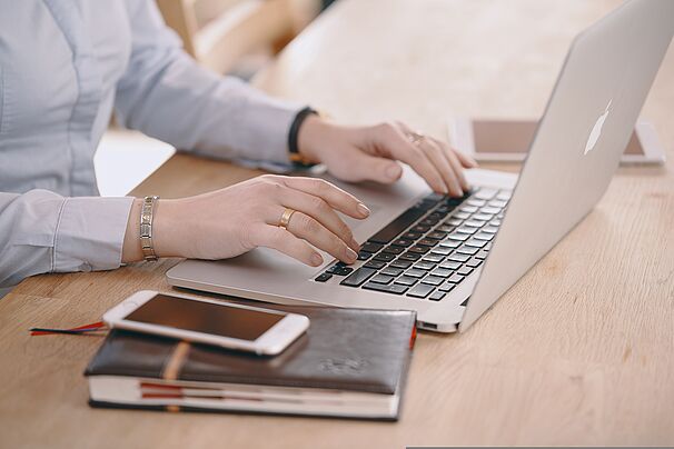 Frau sitzt am Tisch vor ihrem Laptop