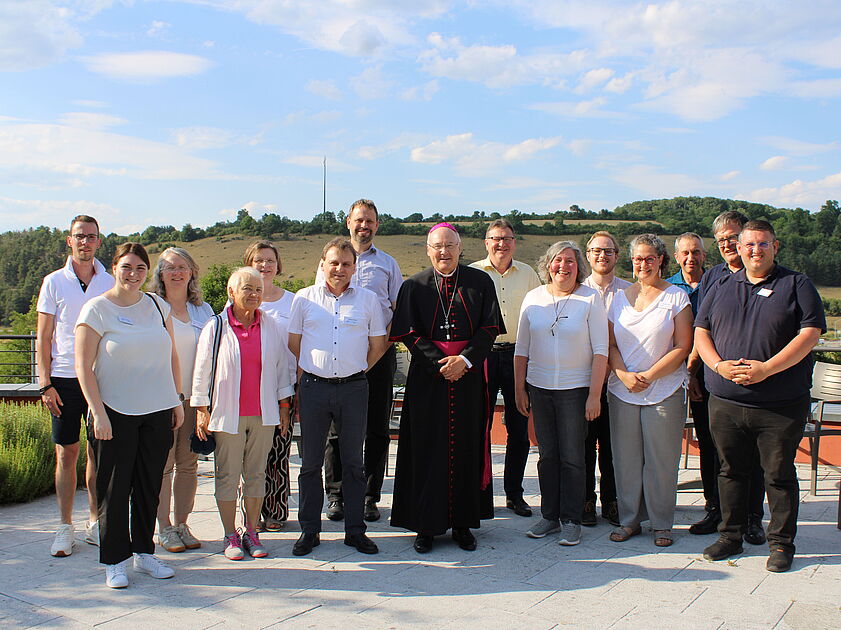 Das Bild zeigt Menschen, die sich zu einem Gruppenfoto um einen Bischof aufgestellt haben.